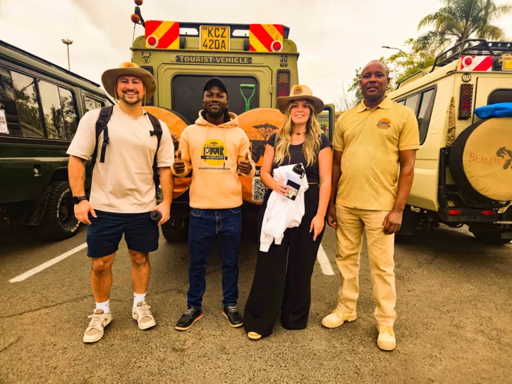 Two PMK guests standing with the safari team beside safari vehicles