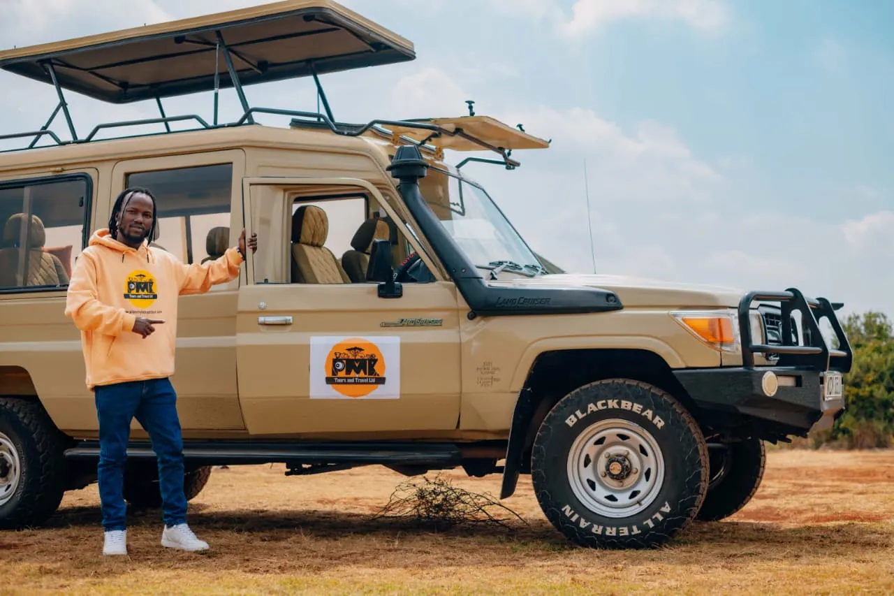 PMK branded safari Land Cruiser with its viewing roof raised and a person standing beside it