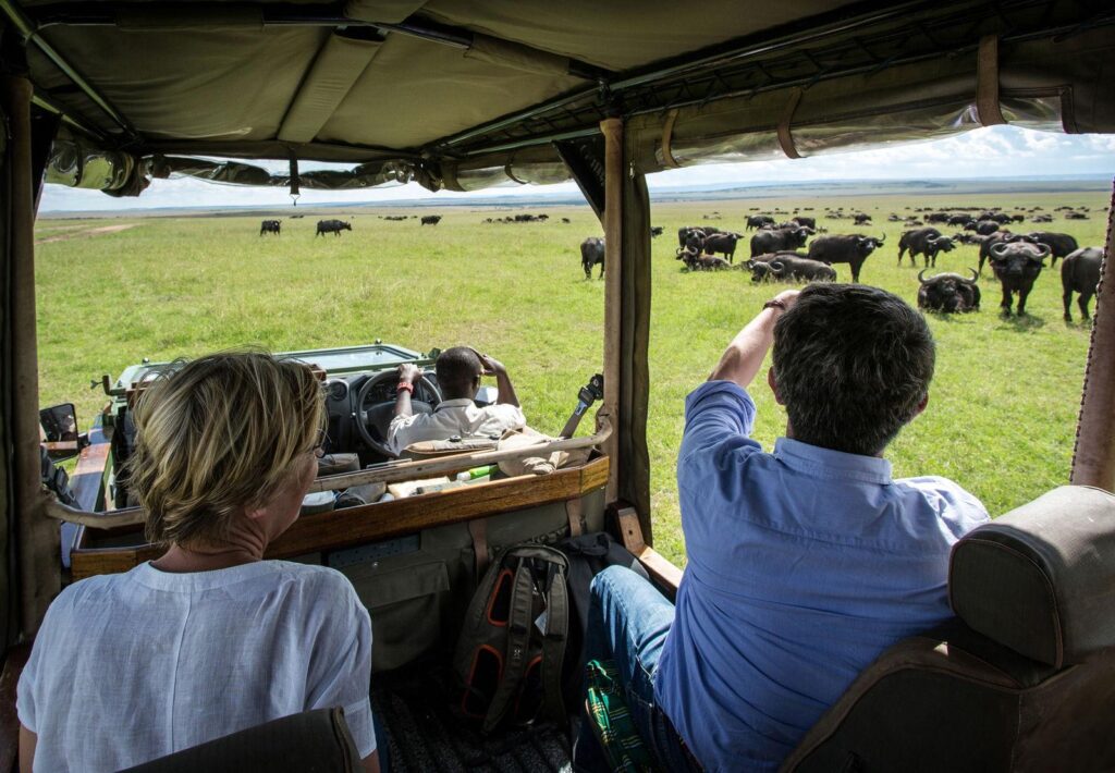 Visitors enjoying a game drive in an open-sided safari vehicle in Kenya.